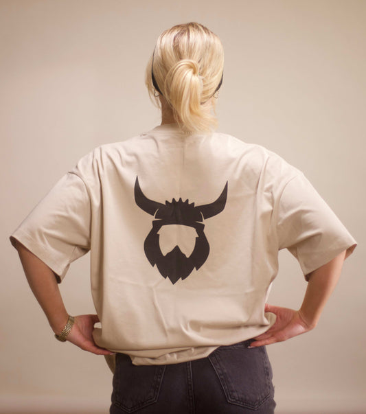 Back view of apricot Viking t-shirt with black Viking helmet and beard logo on the back, worn by a person with blonde hair tied in a ponytail.