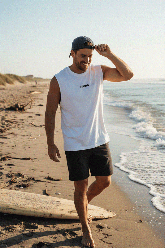 Athletic man with backwards cap wearing white Viking tank at beach